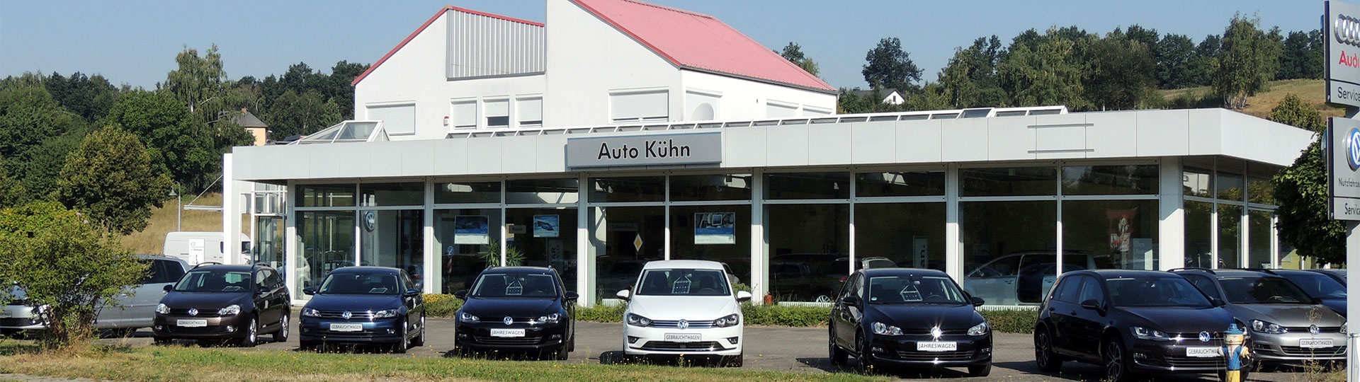 Außenansicht Auto-Kühn Schmölln, Gebäude mit rotem Satteldach und Fahrzeugreihe auf dem Vorplatz